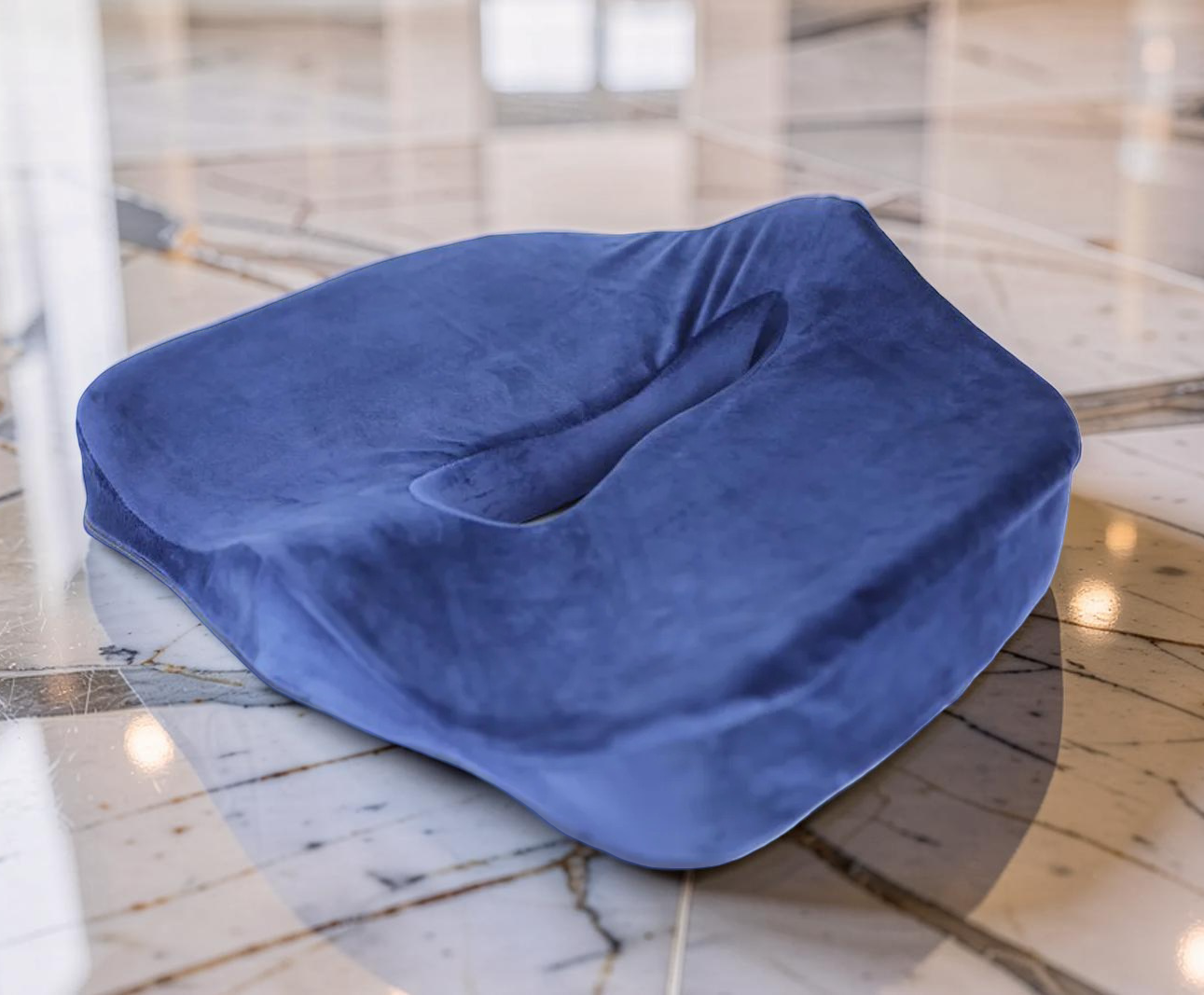 A blue memory foam seat cushion with a cut-out design, placed on a marble floor.