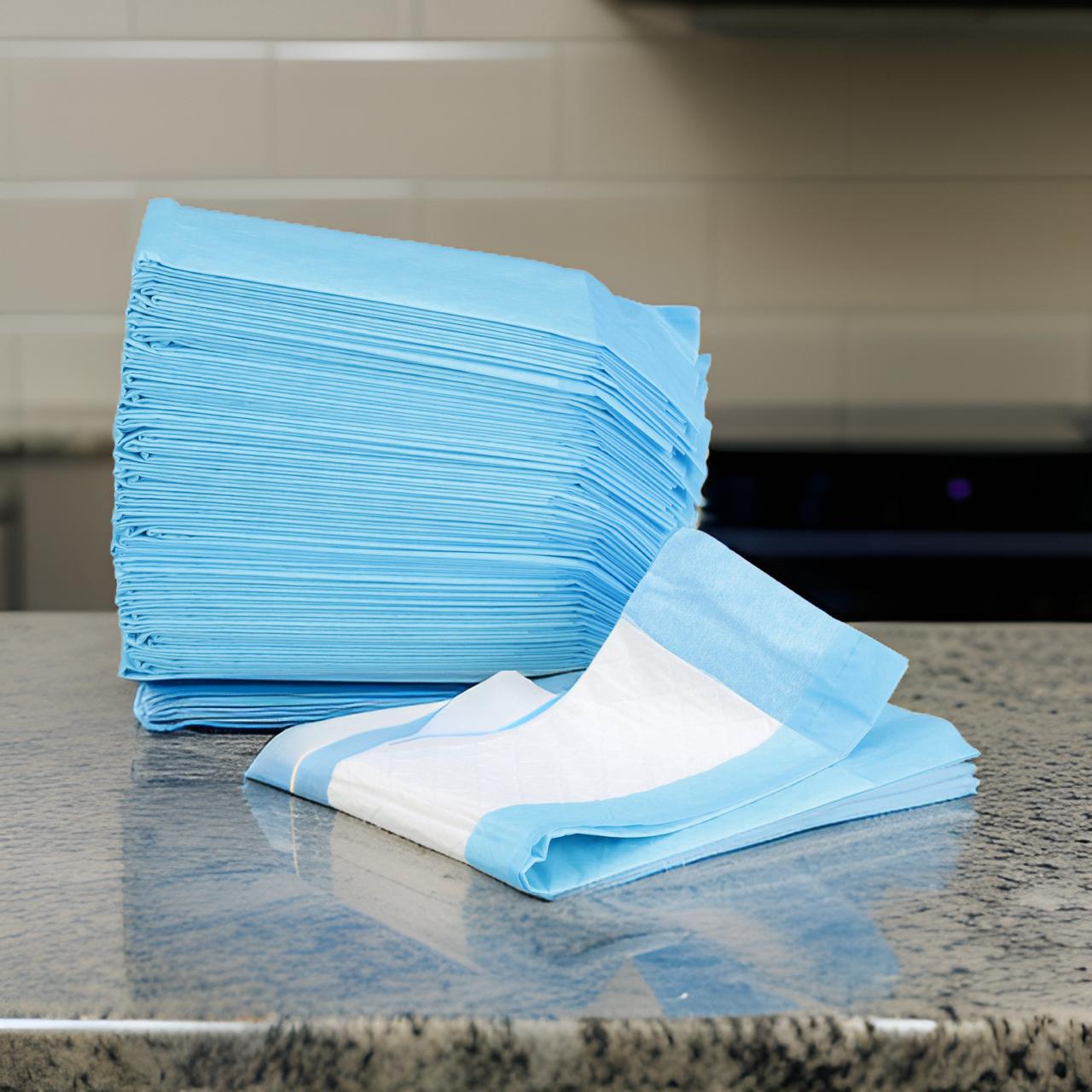 A stack of blue medical exam papers folded neatly, with one partially unfolded, placed on a granite countertop.